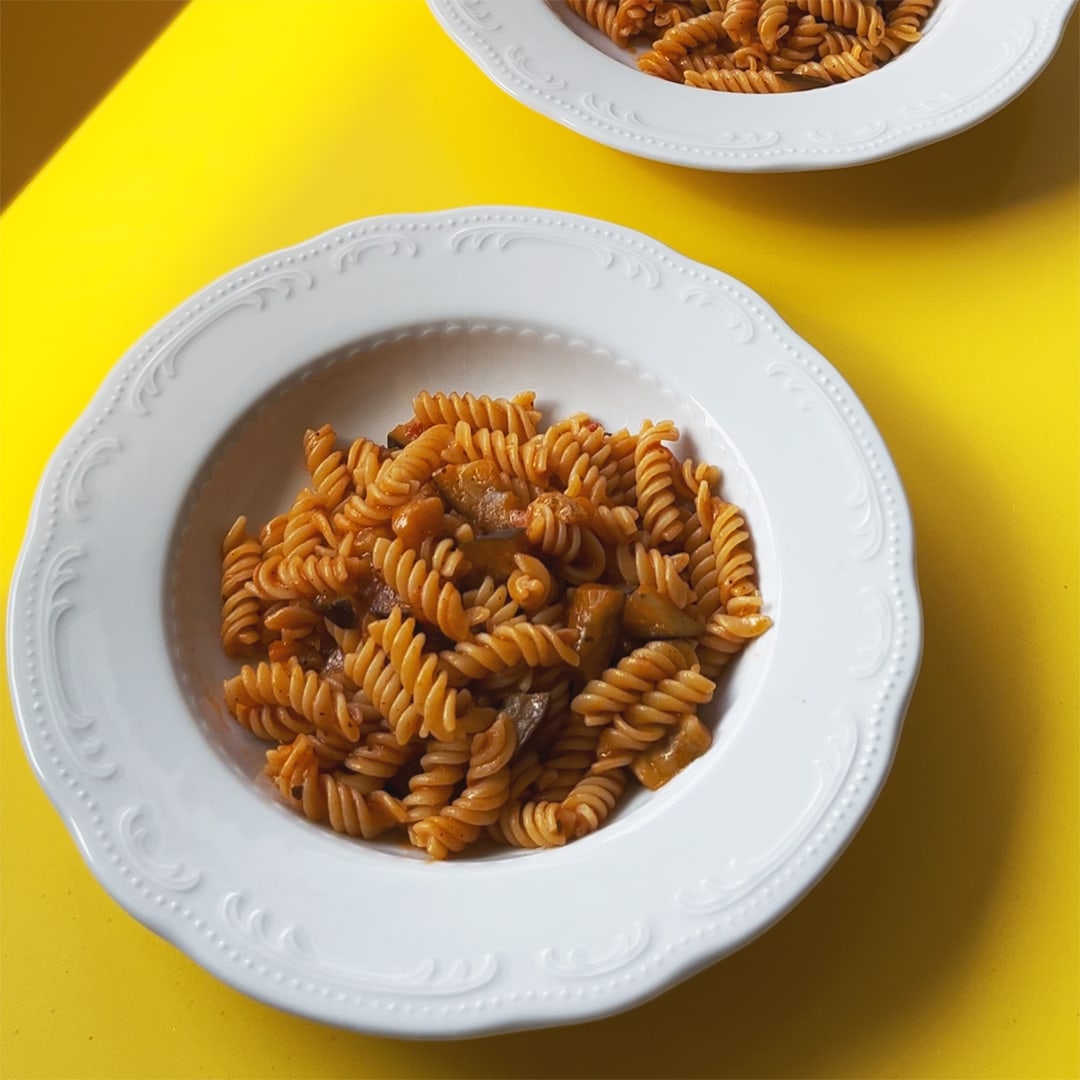 A dish of eggplant pasta on yellow background