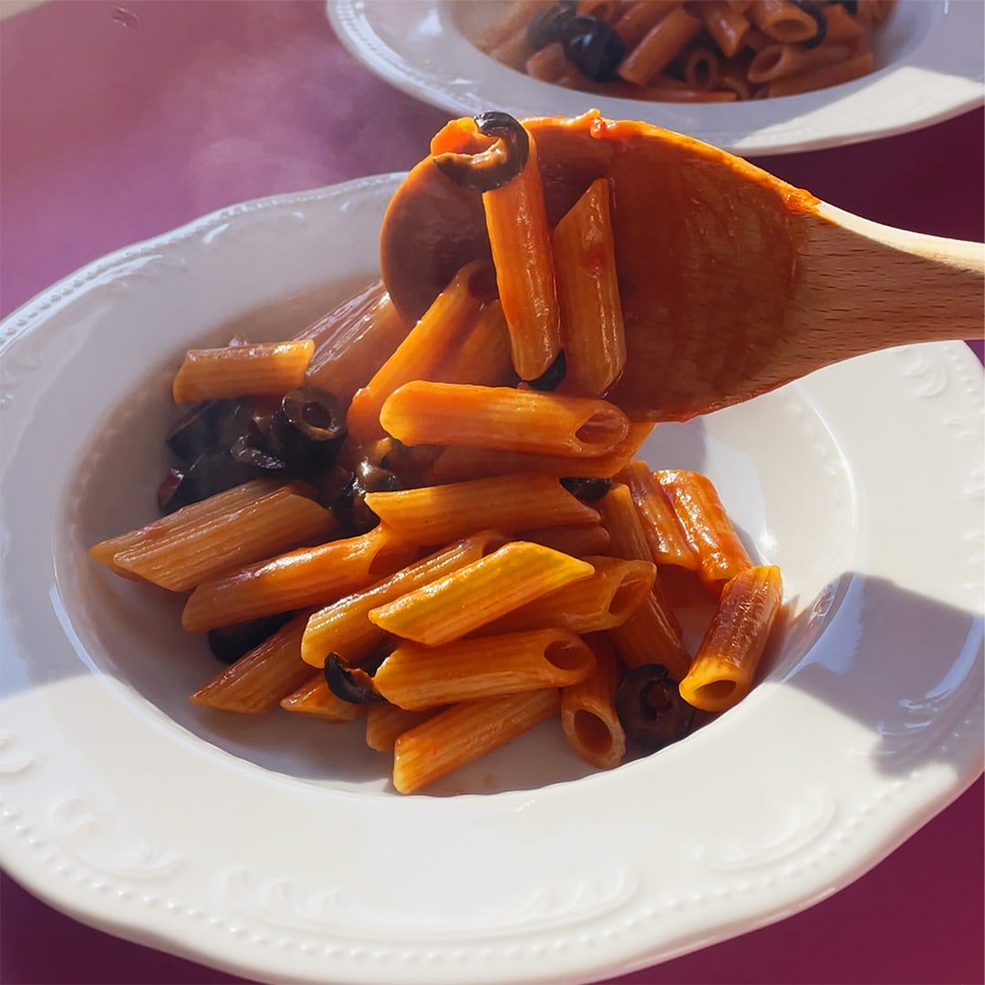 A plate of spicy pasta with black olives