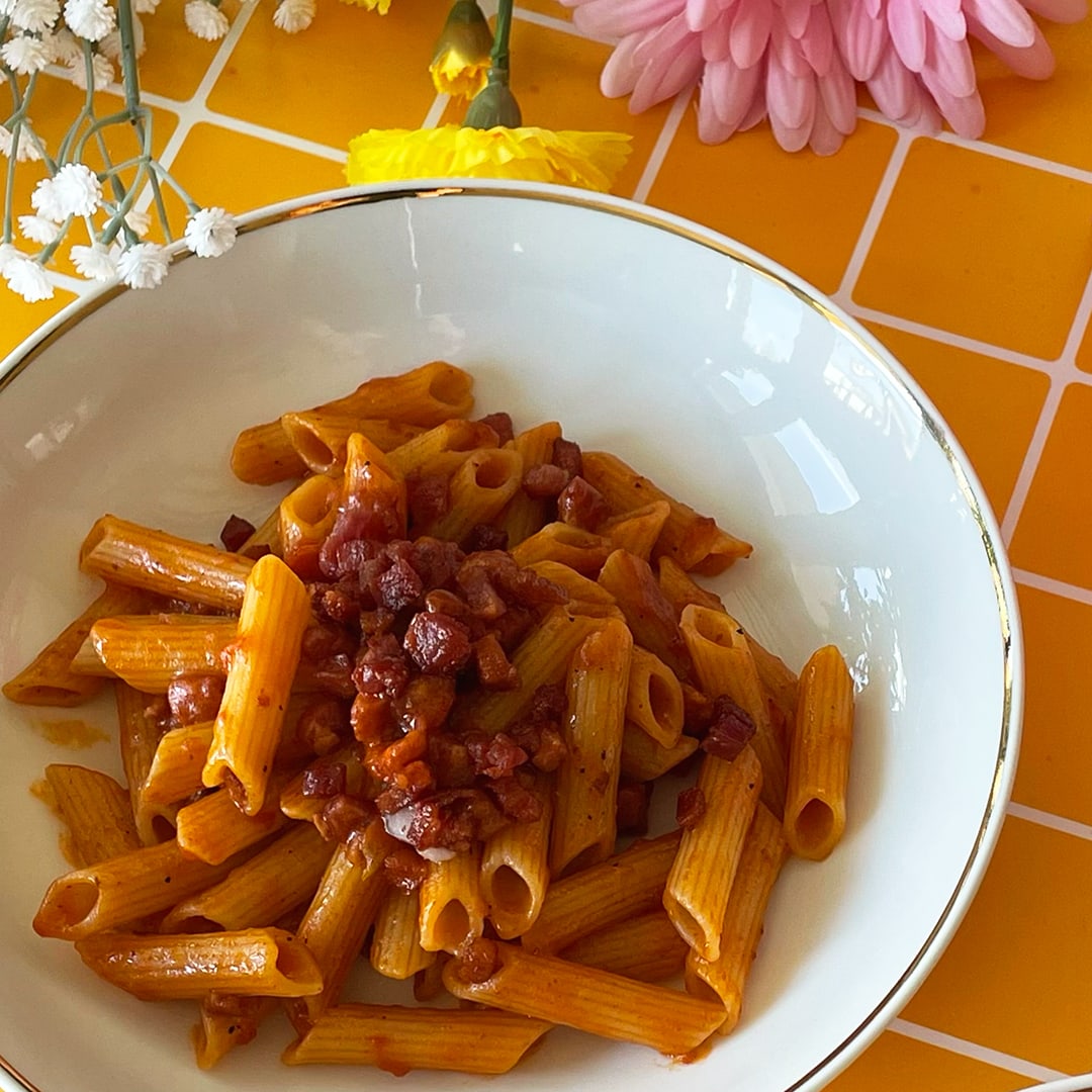 A dish of crispy bacon pasta on orange background