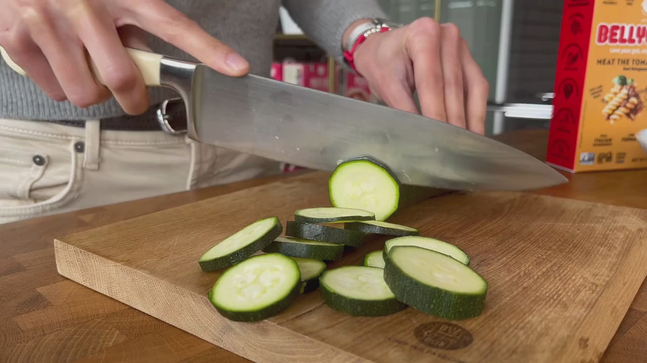 Person who cuts zucchini and cooks gluten-free pasta